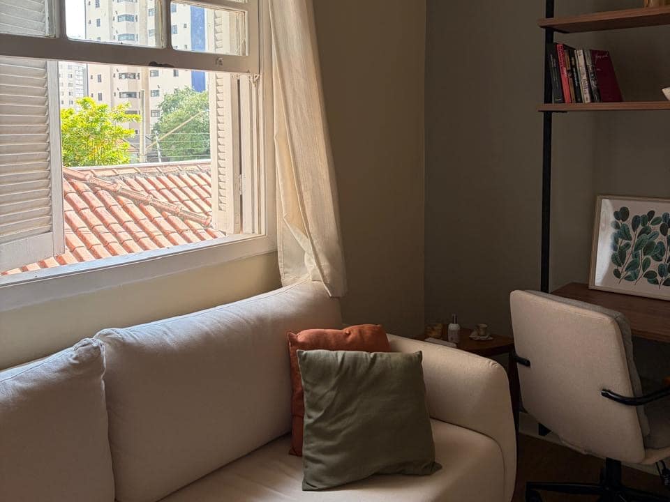 Sala de atendimento do consultório na Pompéia, com sofá claro sob a janela e luz natural